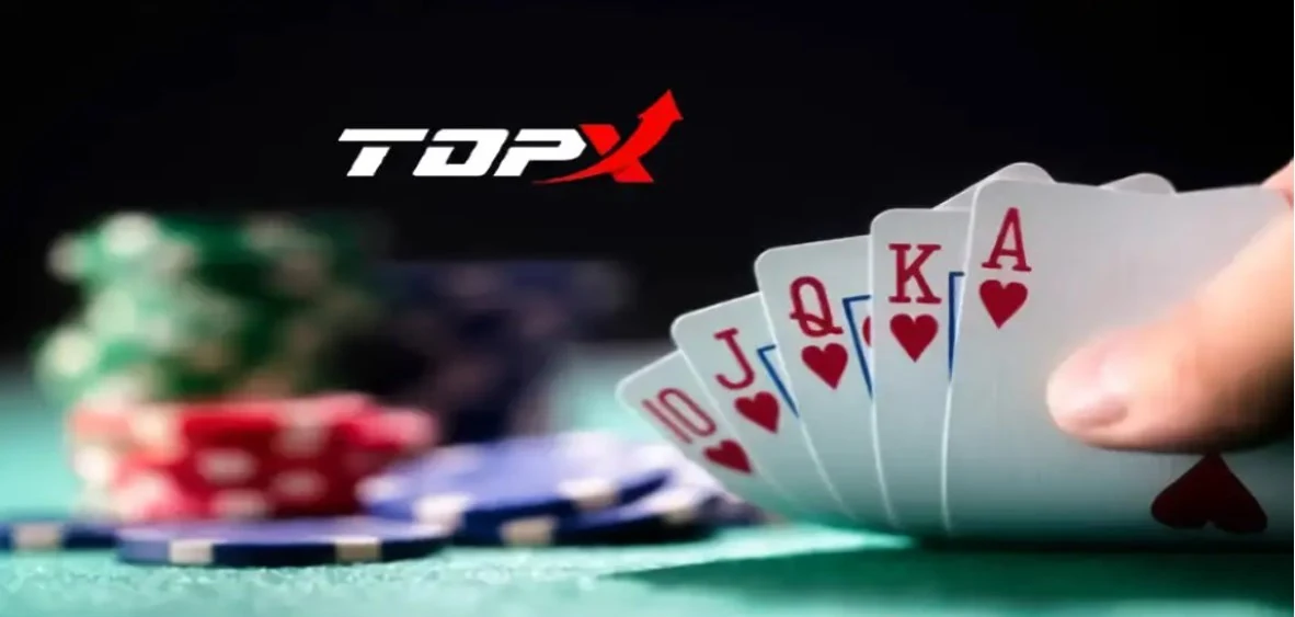 Mão segurando cartas de dez a ás de copas sobre mesa verde, com fichas desfocadas e o logotipo da TopX